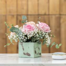 Pink roses in a mint square vase with baby's breath