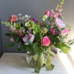 Mixed pink and green flower arrangement in a glass vase with a ribbon