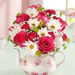 Pink roses and white daisies arranged in a floral teapot