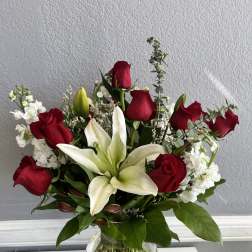 Red roses and white lilies arranged in a clear glass vase