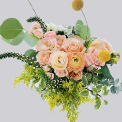Peach and blush roses with yellow accents in a loose bouquet