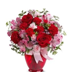 Red and pink flower bouquet in a red vase with a pink ribbon