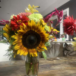 Mixed bouquet with a large sunflower in a glass vase