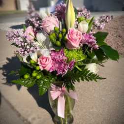Pink and white mixed bouquet in a glass vase with a pink ribbon