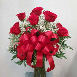Bouquet of red roses with baby's breath in a glass vase and red ribbon