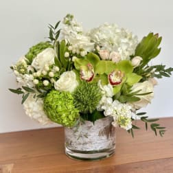 White and green floral arrangement in a glass vase