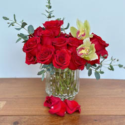 Red roses and pale orchids arranged in a clear glass vase