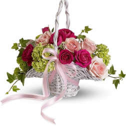 White wicker basket of hot pink and pale pink roses with green hydrangea and a pink ribbon bow