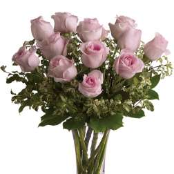 Arrangement of light pink roses with accent foliage in a clear glass vase
