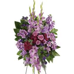 Standing spray of purple and lavender flowers with roses on a metal easel