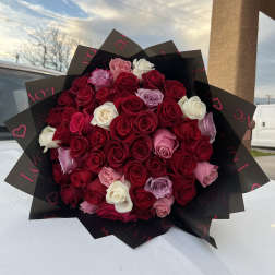 Large bouquet of red, pink, and white roses wrapped in black paper