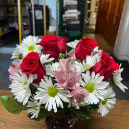 Red roses and white daisies in a dark glass vase