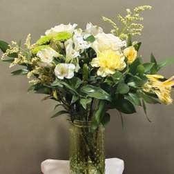 White and yellow flowers arranged in a clear glass vase