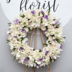 Large floral wreath of white and pale lavender flowers on an easel