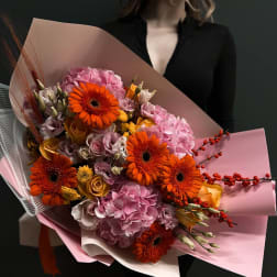 Large bouquet of orange gerbera daisies and pink hydrangeas wrapped in pink paper