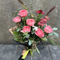 Hand-tied bouquet of pink roses with mixed greenery and small white flowers
