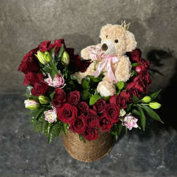 Red rose arrangement with lilies and a teddy bear in a woven basket