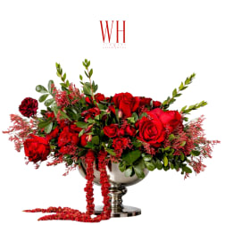 Red rose arrangement in a silver pedestal bowl with trailing red accents