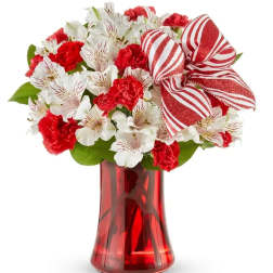 Red and white bouquet in a red glass vase with a striped bow