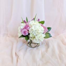 Pink roses and white hydrangeas arranged in a clear glass vase