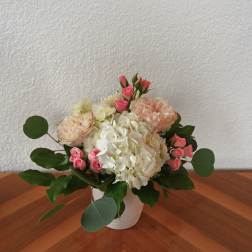 Pink roses and white hydrangeas arranged in a white vase