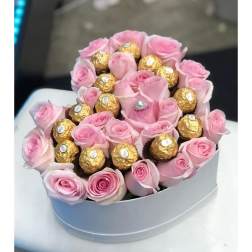 Pink roses arranged with gold-wrapped chocolates in a round box