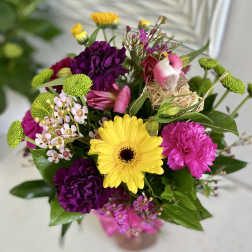 Mixed bouquet with yellow gerbera, purple carnations, and a small bird decoration