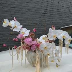 Pink and white orchid arrangement in a ceramic vase