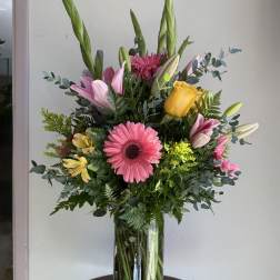 Mixed bouquet in a glass vase with pink, yellow, and white flowers