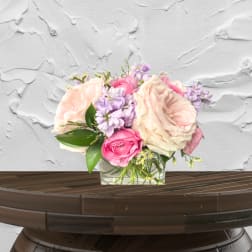 Pink and cream roses with lavender flowers in a glass vase