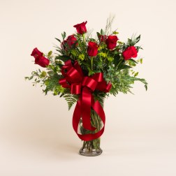 Red roses in a clear glass vase with a large red ribbon