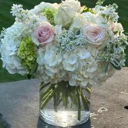 White and blush rose bouquet with hydrangeas in a clear glass vase
