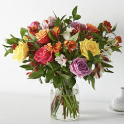 Mixed bouquet of roses and alstroemeria in a clear glass vase