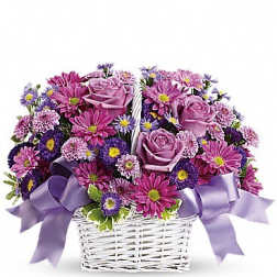 Lavender roses and purple daisies in a white basket with purple bows