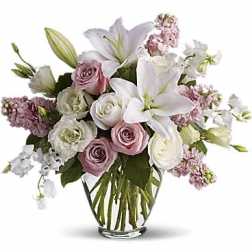 Pink and white roses with lilies in a clear glass vase