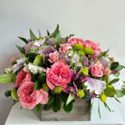 Pink roses and mixed blooms arranged in a wooden box