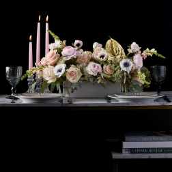 Pink floral centerpiece with candles and gold accent on a table