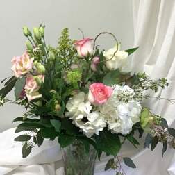 Pink and white roses with white hydrangeas in a glass vase