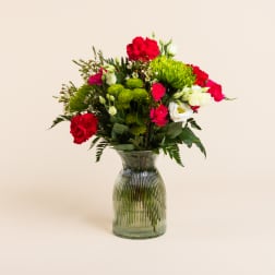 Mixed bouquet of red, pink, white, and green flowers in a glass vase
