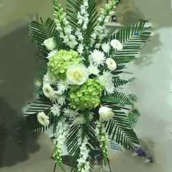 Standing floral spray with white flowers and green hydrangeas on an easel