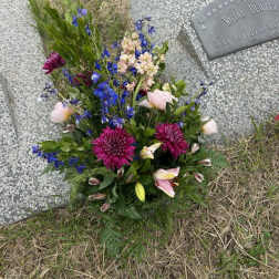 Bouquet of mixed flowers placed beside a gravestone