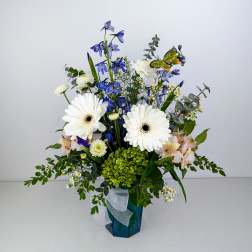 Blue and white floral arrangement in a blue vase with a ribbon