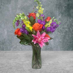 Colorful bouquet of roses, lilies, and stock in a glass vase