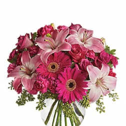Pink lilies and gerbera daisies in a clear glass vase
