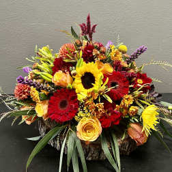 Bright mixed flower arrangement with sunflowers and red gerberas in a wood base
