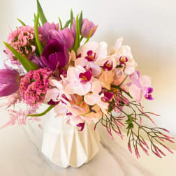 Pink and purple bouquet with orchids and tulips in a white vase
