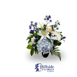 White lilies, blue hydrangea, and purple flowers in a black vase