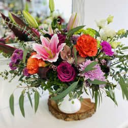 Colorful mixed bouquet in a white vase with lilies, roses, and chrysanthemums
