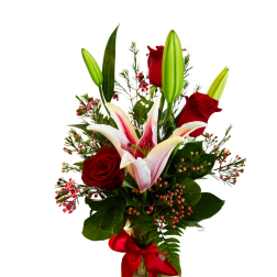 Red roses and pink lilies in a glass vase with a red ribbon