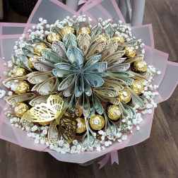 Bouquet of folded money and gold-wrapped chocolates with small white blooms, wrapped in pink paper